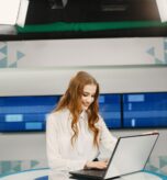 Tv present at studio preparing for new broadcasting. Smiling girl in white shirt sitting at table .