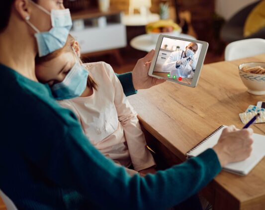 Close-up of black pediatrician advising mother during video call Close-up of mother using digital tablet while talking with pediatrician about her ill daughter during coronavirus pandemic.